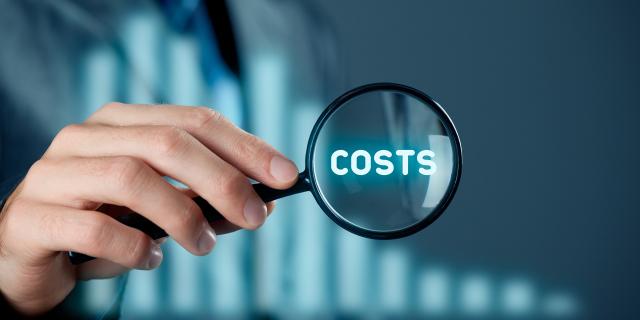 Kuva suurennuslasista jonka sisällä on sana "costs" = kustannukset
